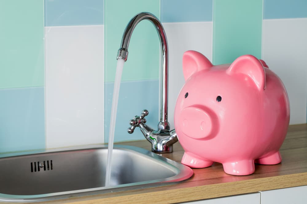 Pink Piggy bank next to an open faucet
